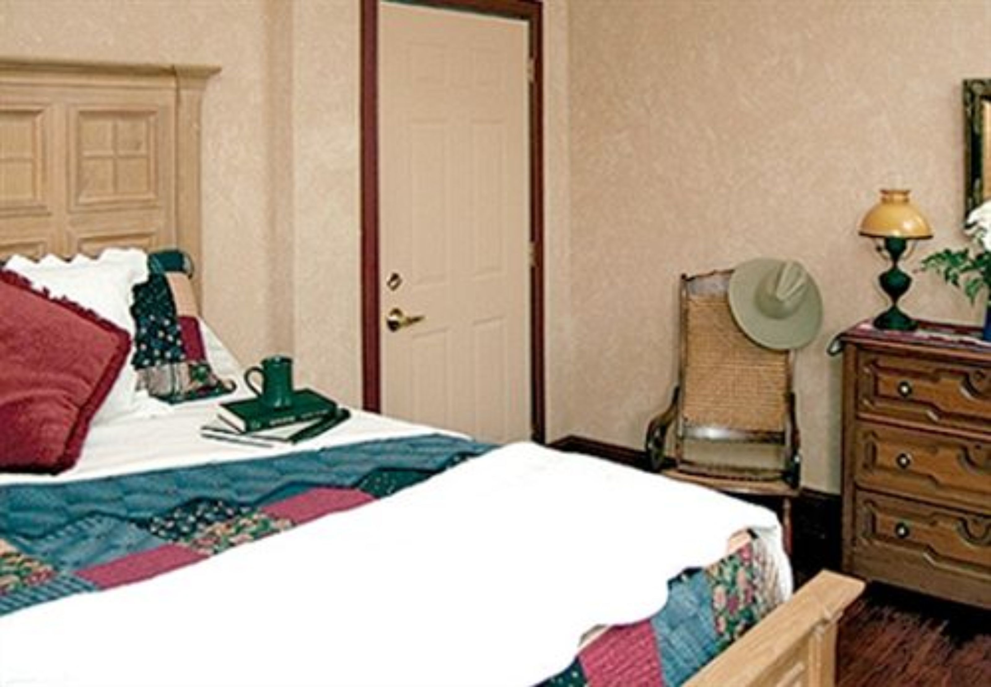 Un dormitorio con cama, cómoda, silla y lámpara.