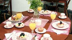 A breakfast table set with plates of food, glasses of orange juice, and a vase of flowers. - The Brafferton Inn (Gettysburg)