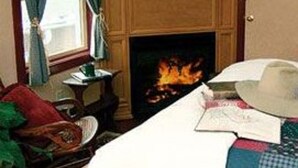 A room with a bed, a fireplace, a television, and a window with curtains. - The Brafferton Inn (Gettysburg)