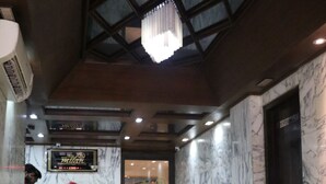 A reception area with a marble floor, a reception desk, a chandelier, and a leather sofa. - Hotel Milan International (Mumbai)