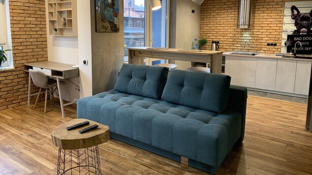 A modern living space with a sofa, a desk, and a kitchen area. - KievRent Apartments (Kyiv)