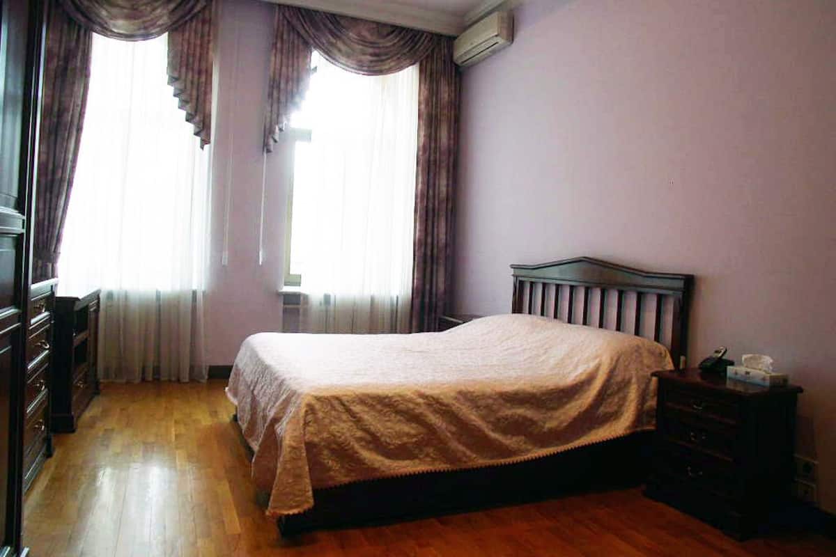 A bedroom with a bed, wooden dresser, and a nightstand.