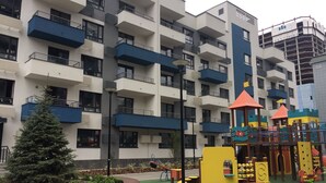 A multi-story residential building with balconies, a playground with colorful play structures, and a Christmas tree. - KievRent Apartments (Kyiv)