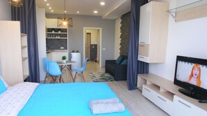 A modern hotel room with a large bed, a TV, a desk, and a dining area. - KievRent Apartments (Kyiv)