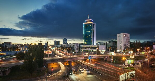 A cityscape at dusk with a prominent skyscraper, busy roads, and modern buildings.