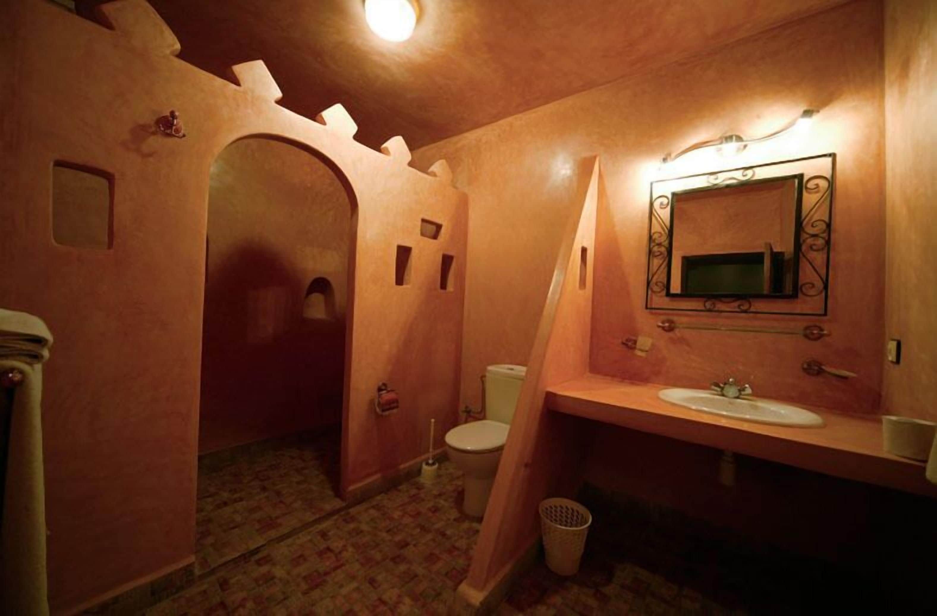 Un baño con un arcoado al estilo castillo, un lavamanos y un inodoro.