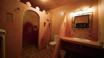 Un baño con un arcoado al estilo castillo, un lavamanos y un inodoro.