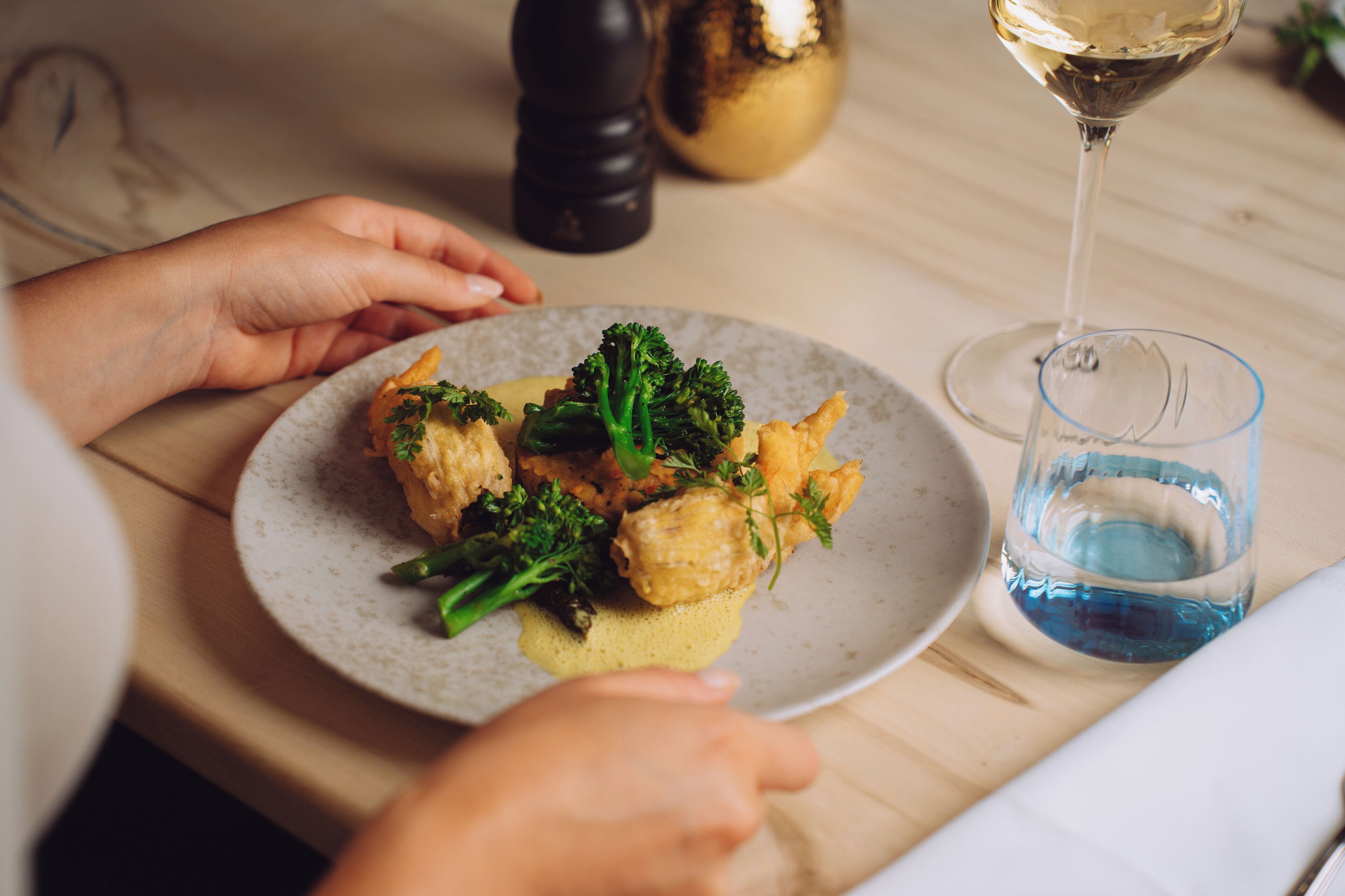 Un tavolo da pranzo con un piatto di cibo, un bicchiere d'acqua e un calice di vino.