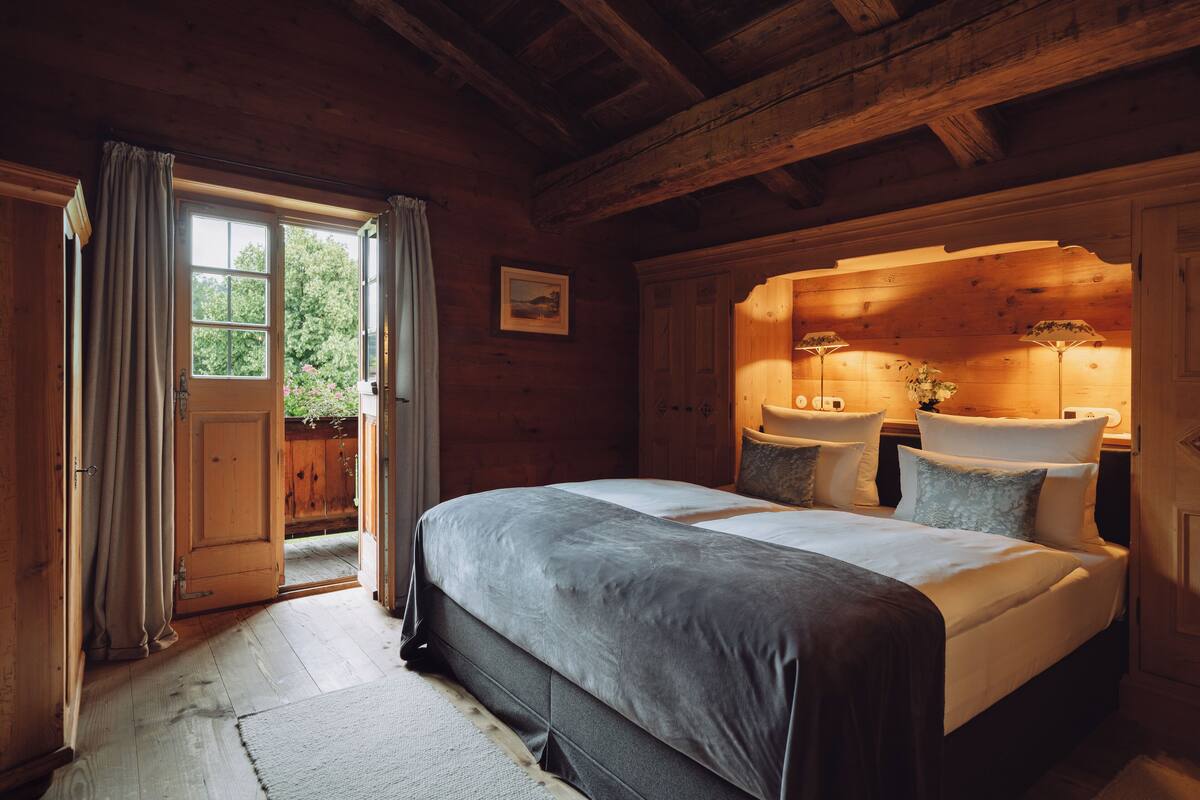 Une chambre à coucher en bois, avec un grand lit, une porte en bois et une vue sur l’extérieur.