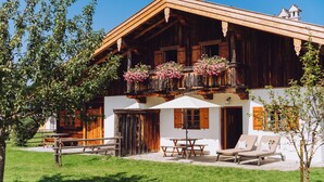 Un chalet en bois doté d’un balcon, d’un espace extérieur aménagé et d’une façade blanche.