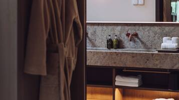 A bathroom with a robe hanging on a rack, a sink with toiletries, and a mirror.