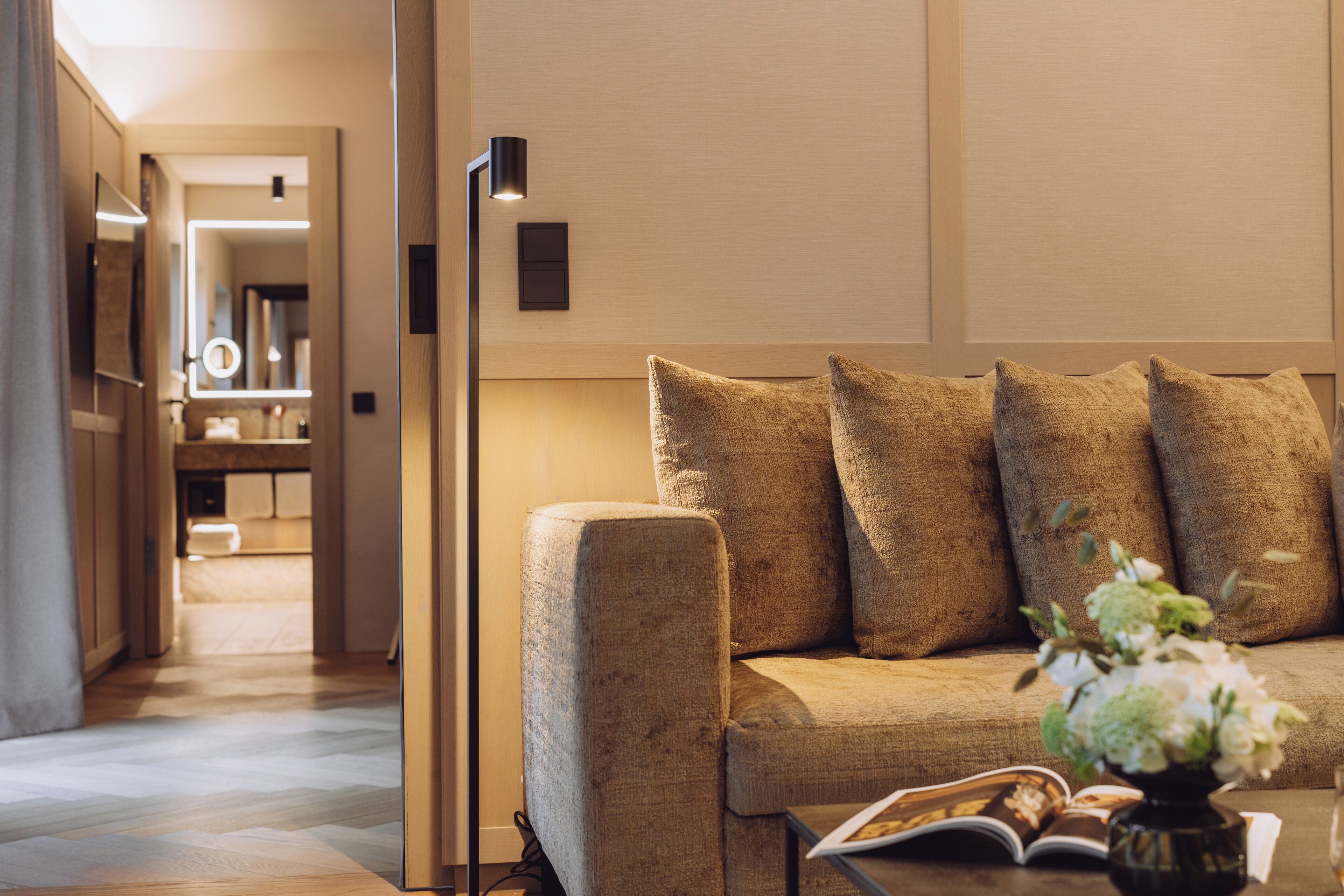 A modern living room with a sofa, a floor lamp, and a vase with flowers.
