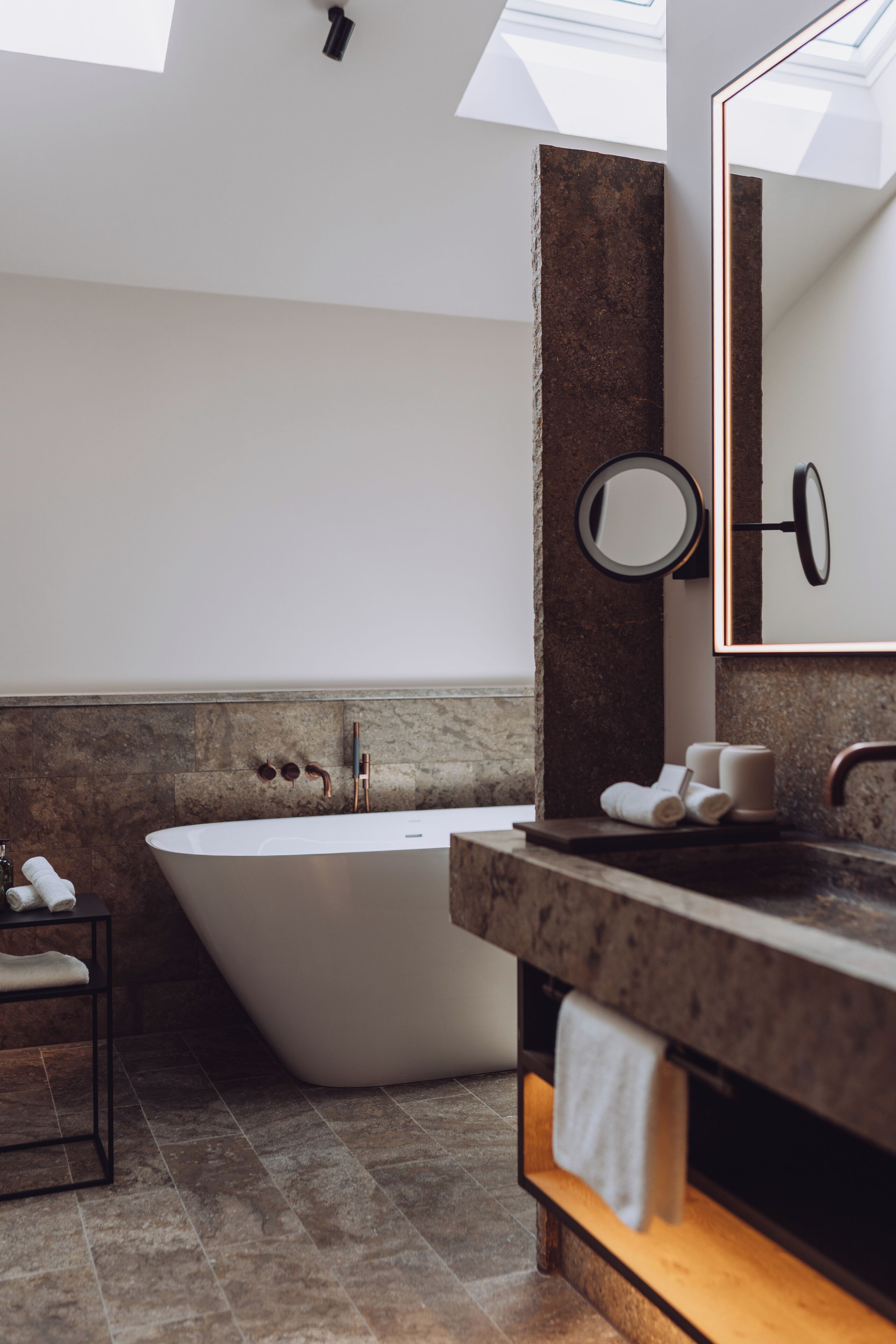 A modern bathroom with a freestanding bathtub, a large mirror, and a wooden vanity.