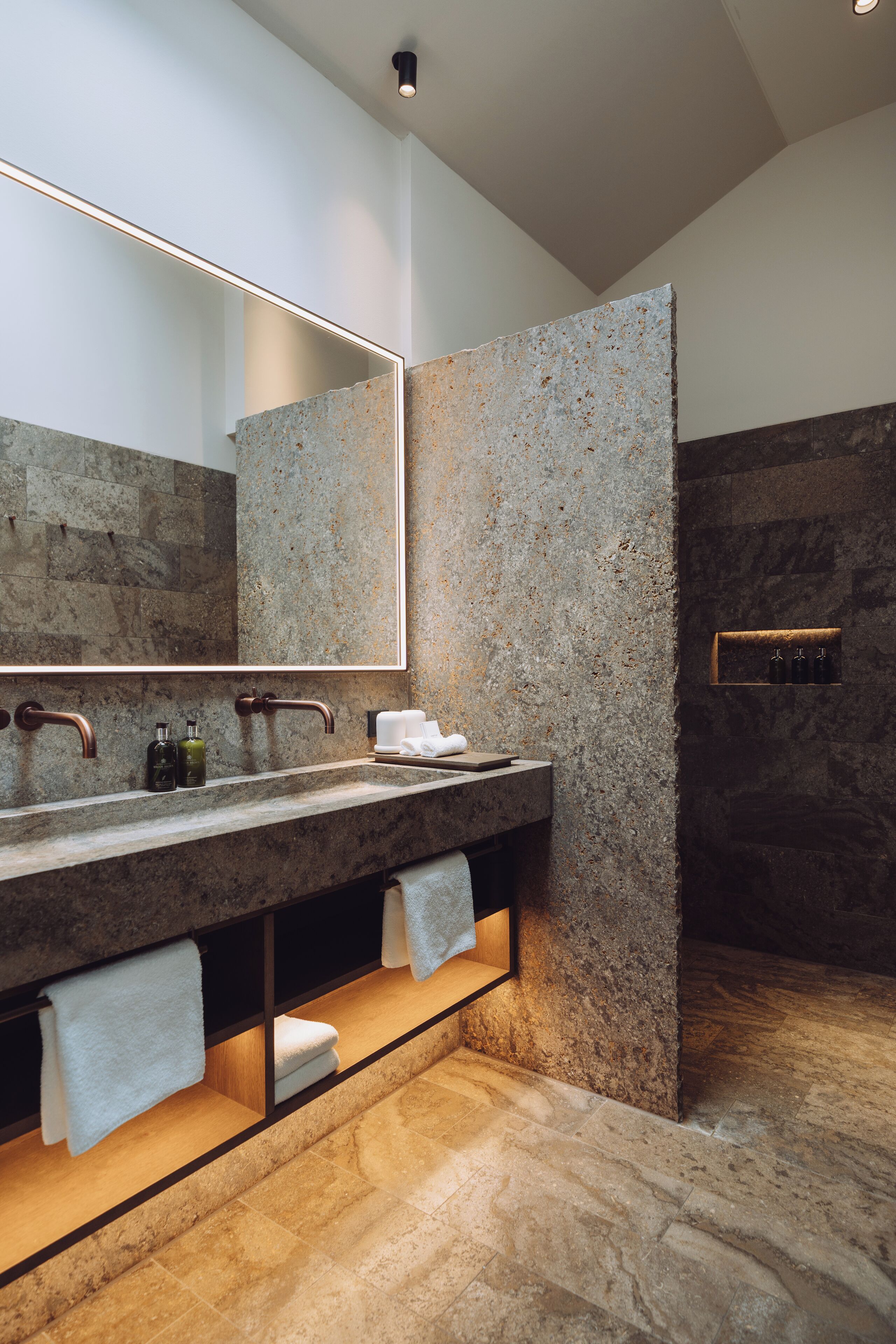Un baño moderno con encimera de granito, un espejo grande y zona de ducha integrada.