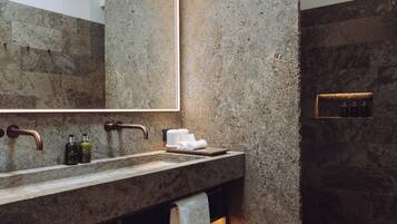 Un baño moderno con encimera de granito, un espejo grande y zona de ducha integrada.