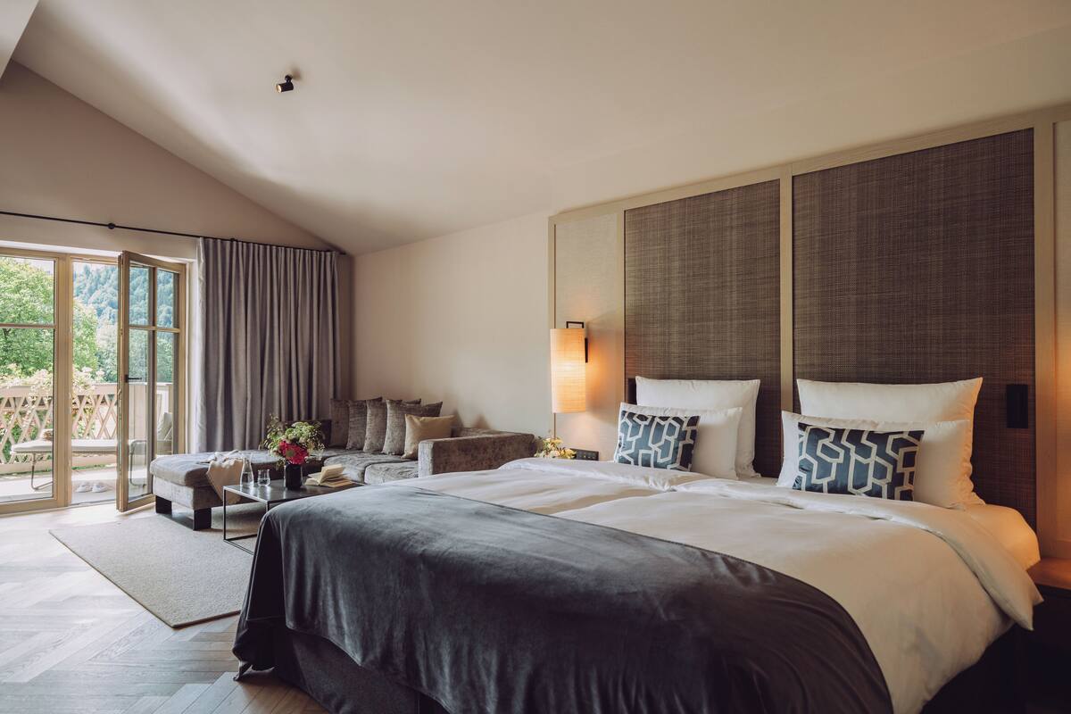 Une chambre d’hôtel moderne, dotée d’un grand lit, d’un canapé, d’un bureau et offrant une vue sur l’extérieur.