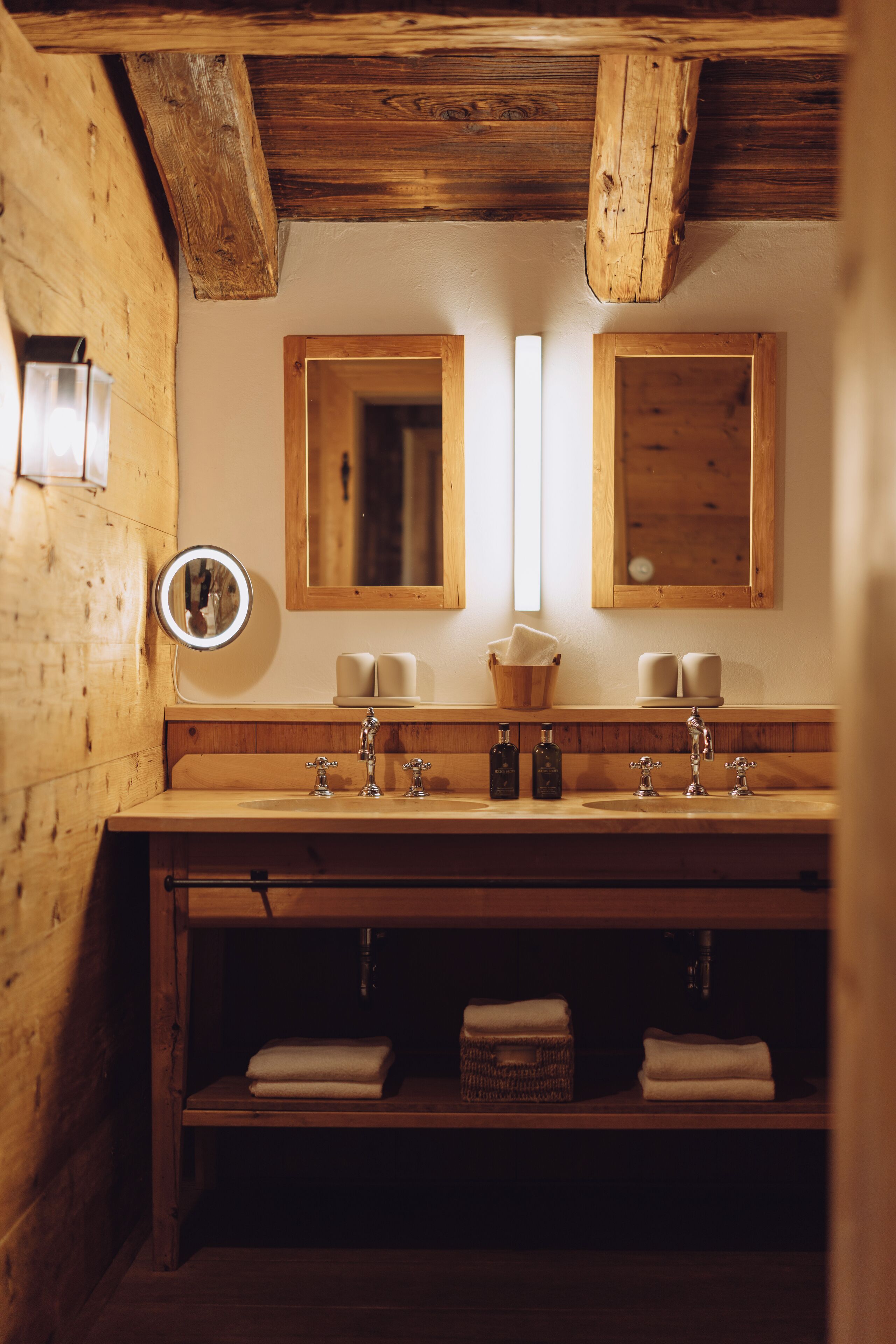 Ein Badezimmer aus Holz mit zwei Waschbecken, einem Spiegel und einem Ablagebereich mit Handtüchern.