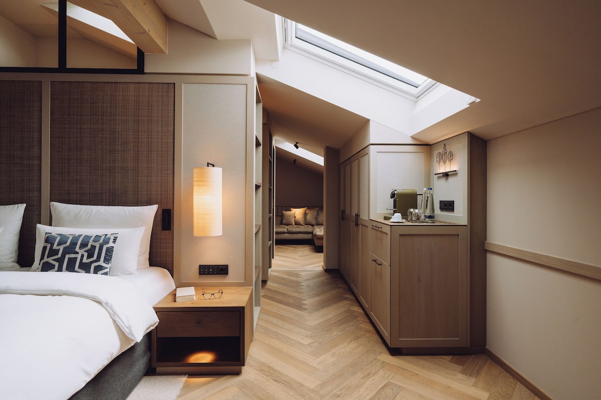 Une chambre à coucher moderne avec une lucarne, une table de chevet avec des lunettes, une commode et une armoire.
