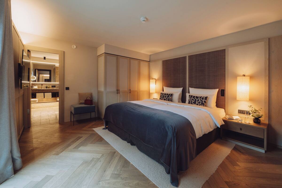 Une chambre d’hôtel moderne avec un grand lit, des lampes de chevet, une table de chevet, un miroir et une armoire.