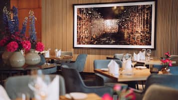 Een restaurant met een groot stadsbeeld in een lijst aan de muur, houten lambrisering en moderne zitplaatsen.