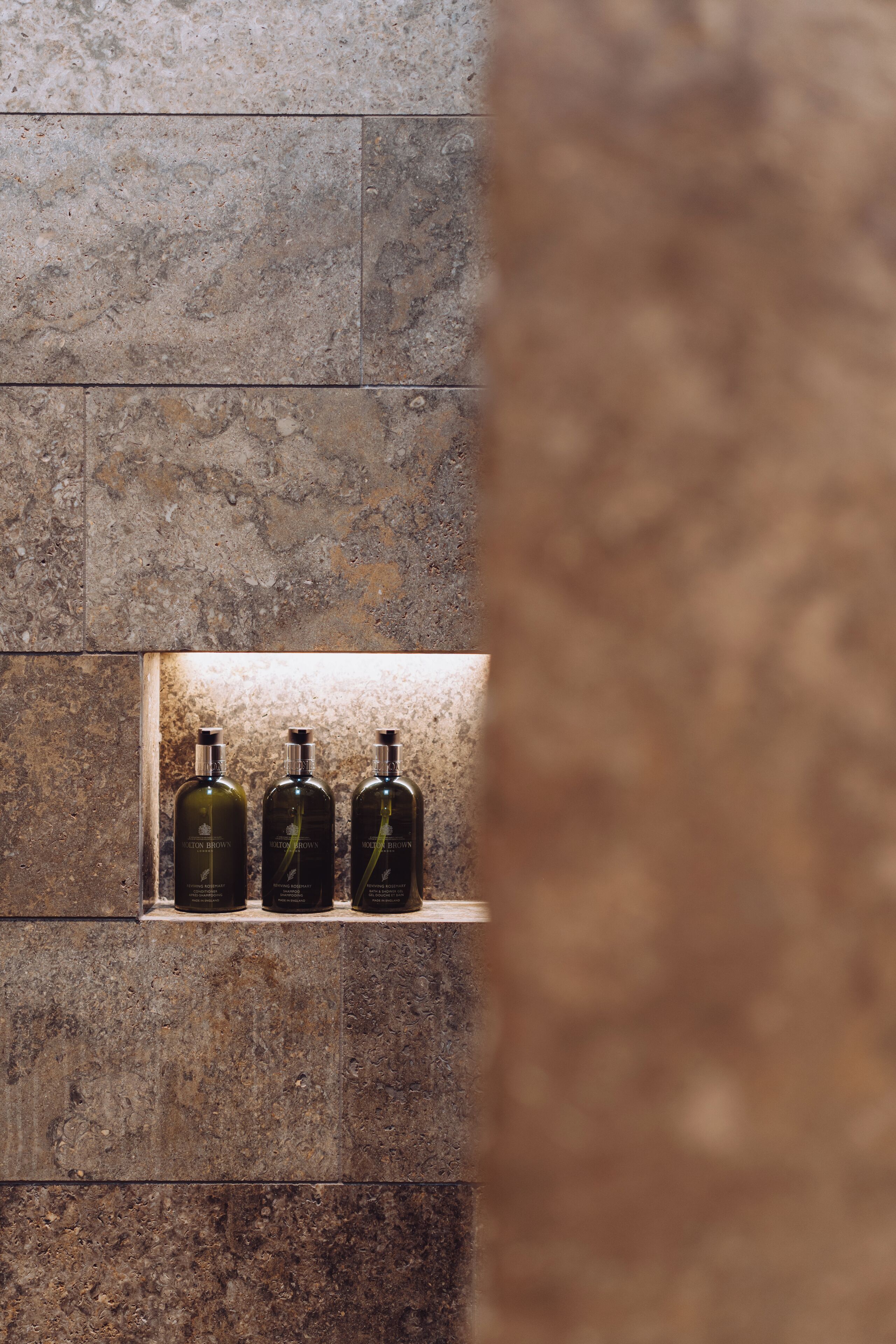 Un muro de piedra con tres botellas de loción.