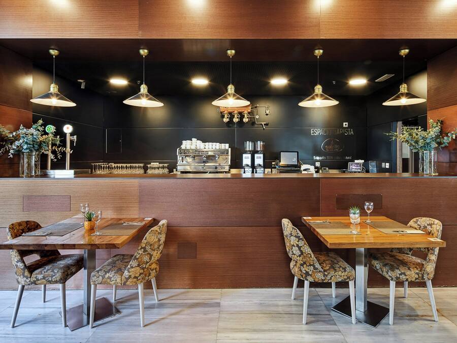 Ein modernes Café mit Holztischen und -stühlen, einer Kaffeebar und Pendelleuchten.