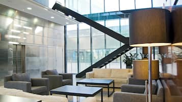 A modern lobby with a staircase, seating area, and a large window.