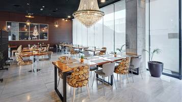 Un restaurante moderno con candelabro, mesas de madera y sillas estampadas.