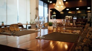 A restaurant interior with long tables, chairs, and a hanging light fixture. - Hotel Sercotel JC1 Murcia (Murcia)