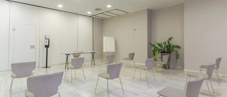 Una sala de conferencias con una pizarra, una mesa y varias sillas estampadas.