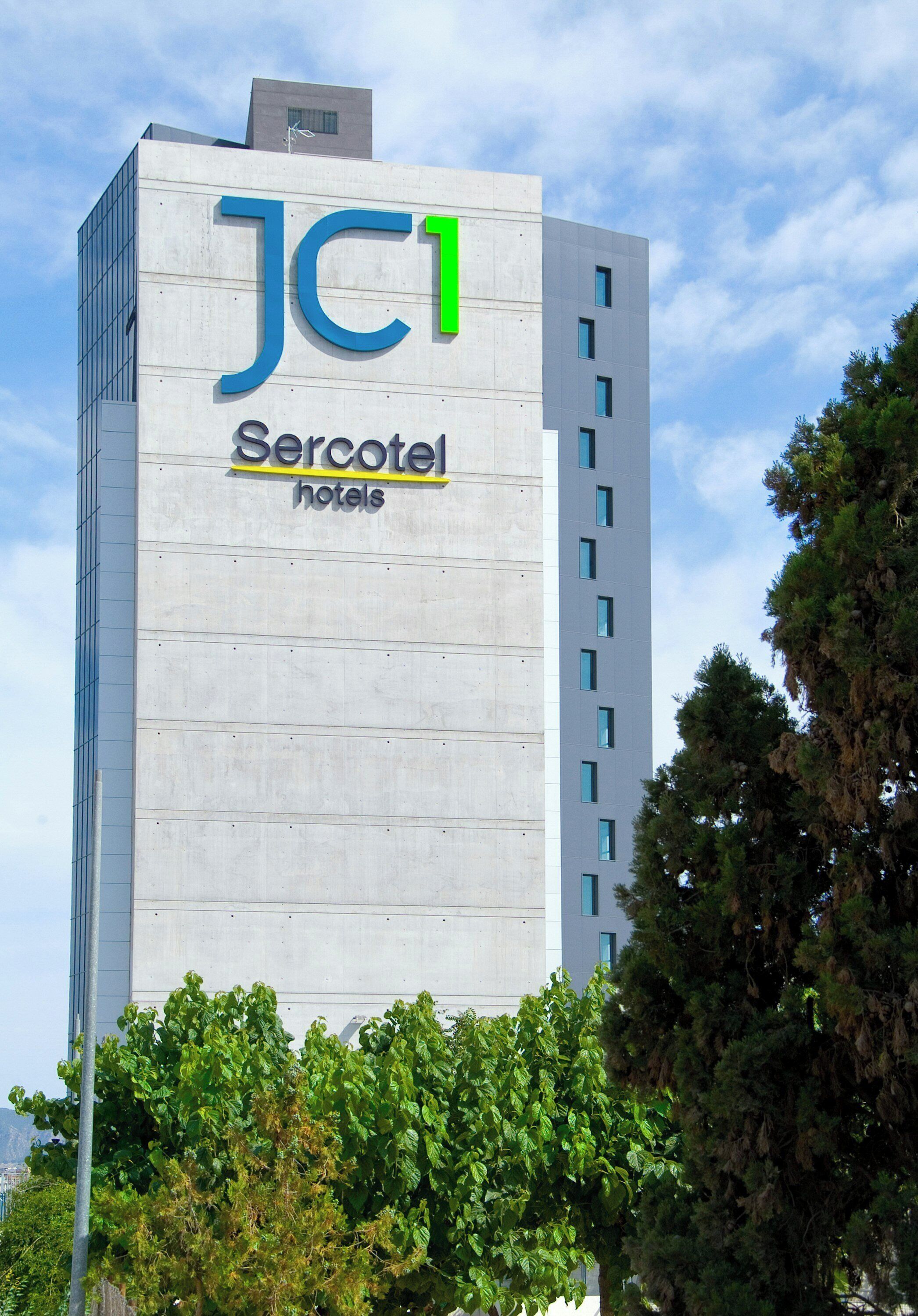 A tall building with a sign for 'JC1 Sercotel hotels' on its facade.