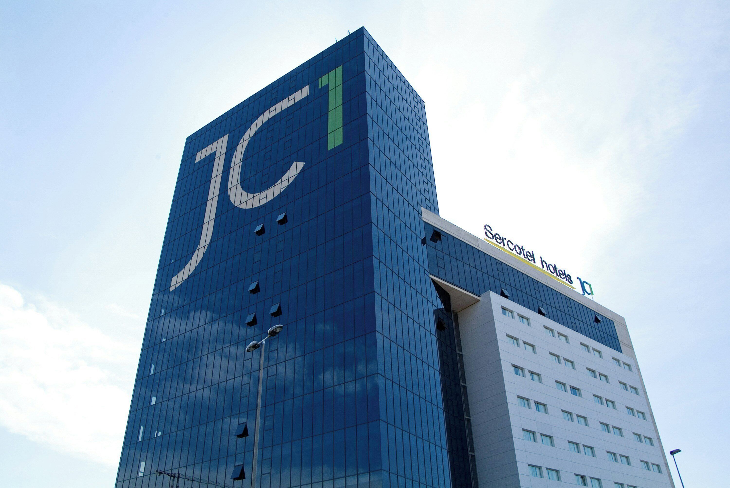 A modern building with a prominent 'JC' logo on the facade.
