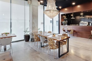 Un comedor moderno con una mesa larga, sillas y una araña.