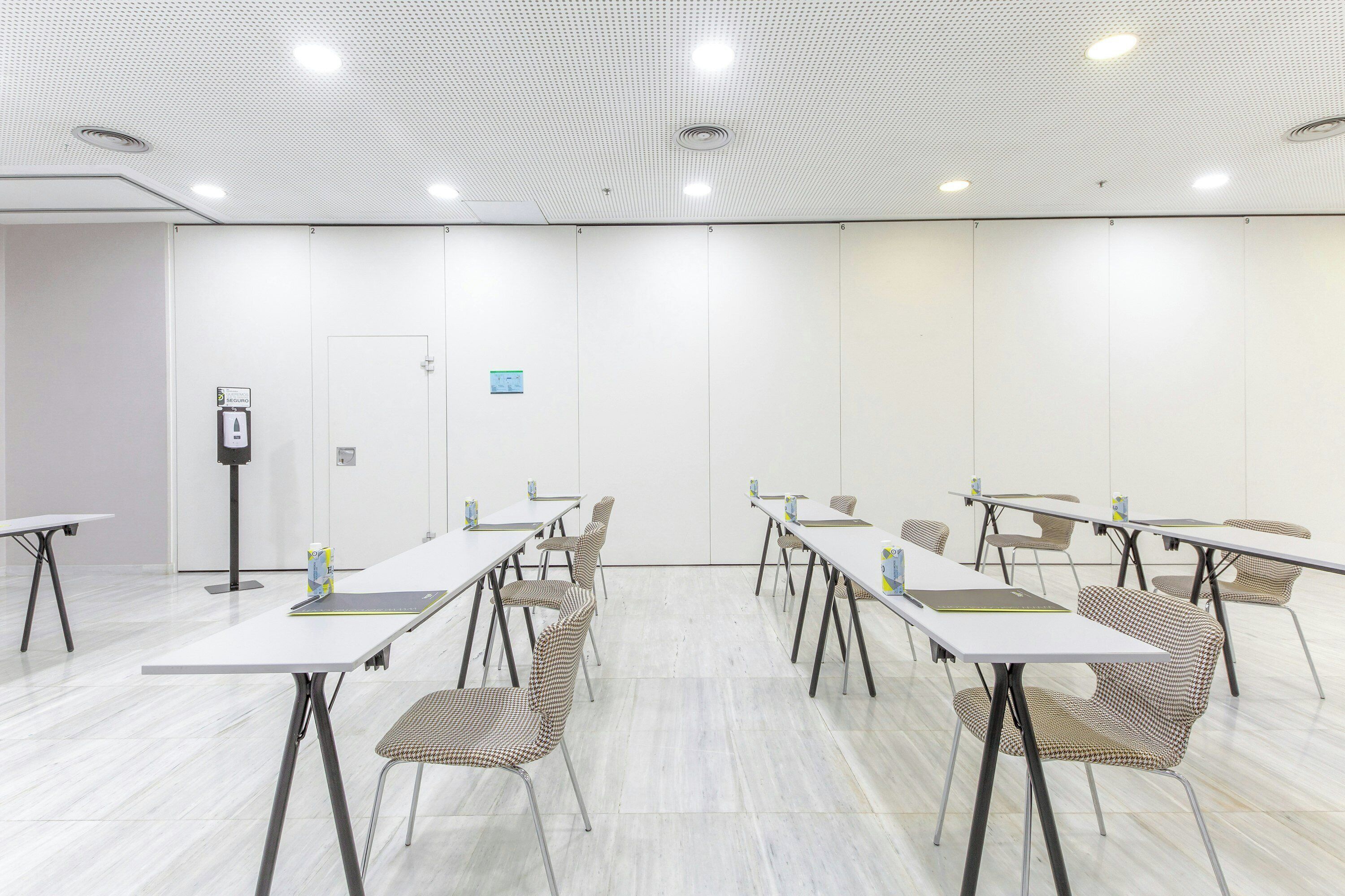A conference room with white tables, chairs, and a whiteboard.