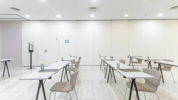 A conference room with white tables, chairs, and a whiteboard.