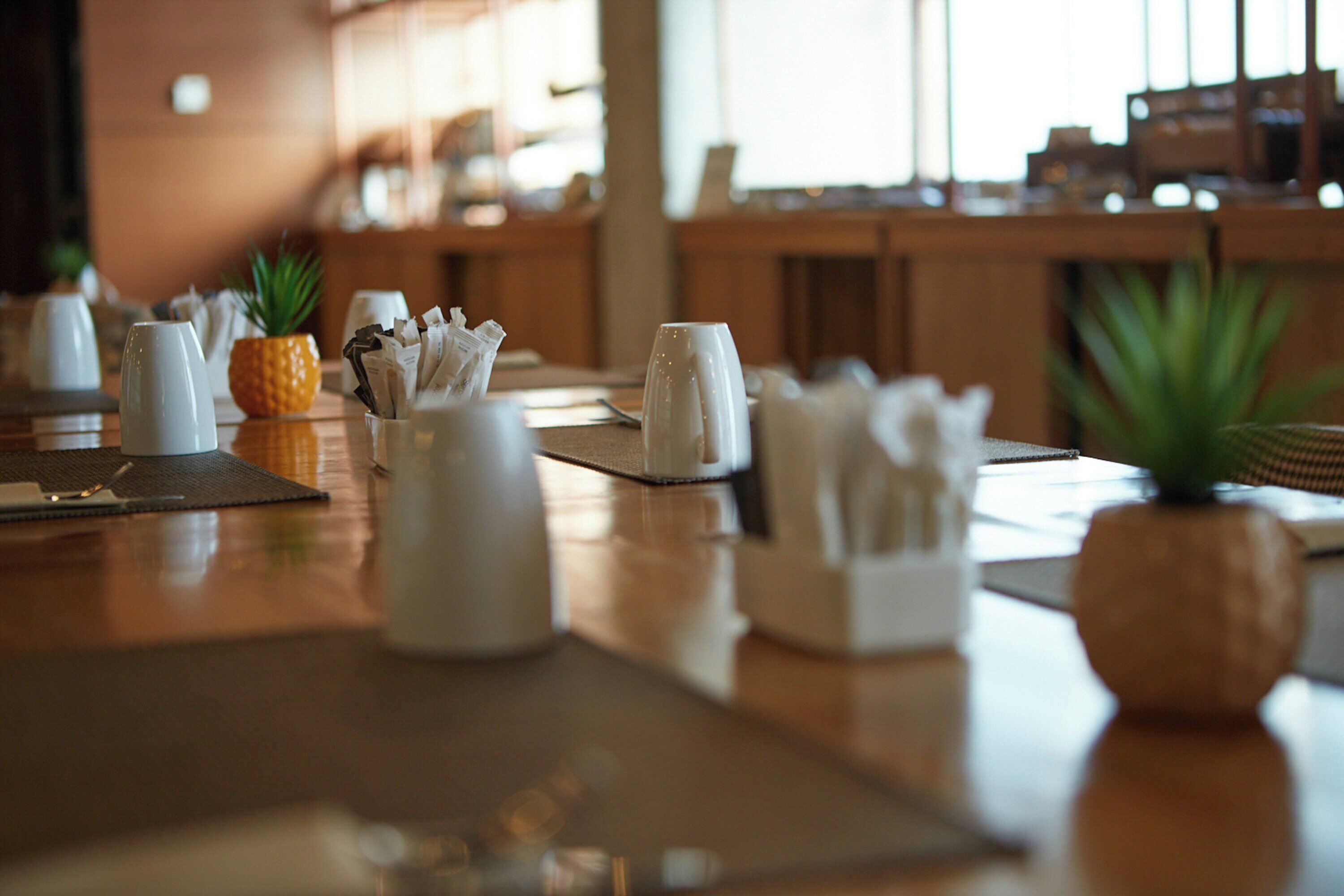 A restaurant table with a pineapple centerpiece, a coffee cup, and a napkin holder.