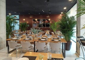 Un restaurante con varias mesas, sillas y plantas en macetas.