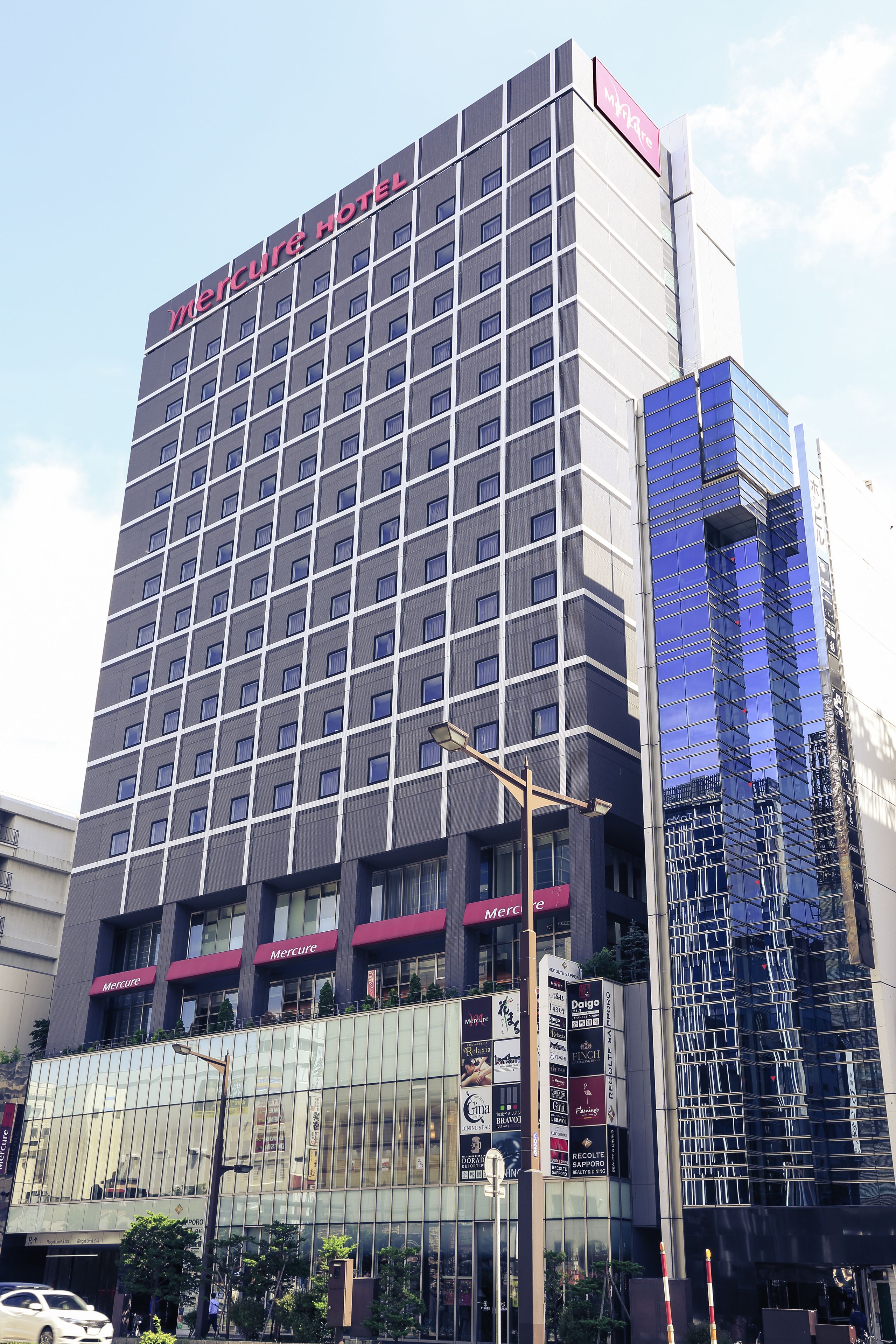 A tall hotel with a modern design, featuring a prominent 'Mercure Hotel' sign at the top.