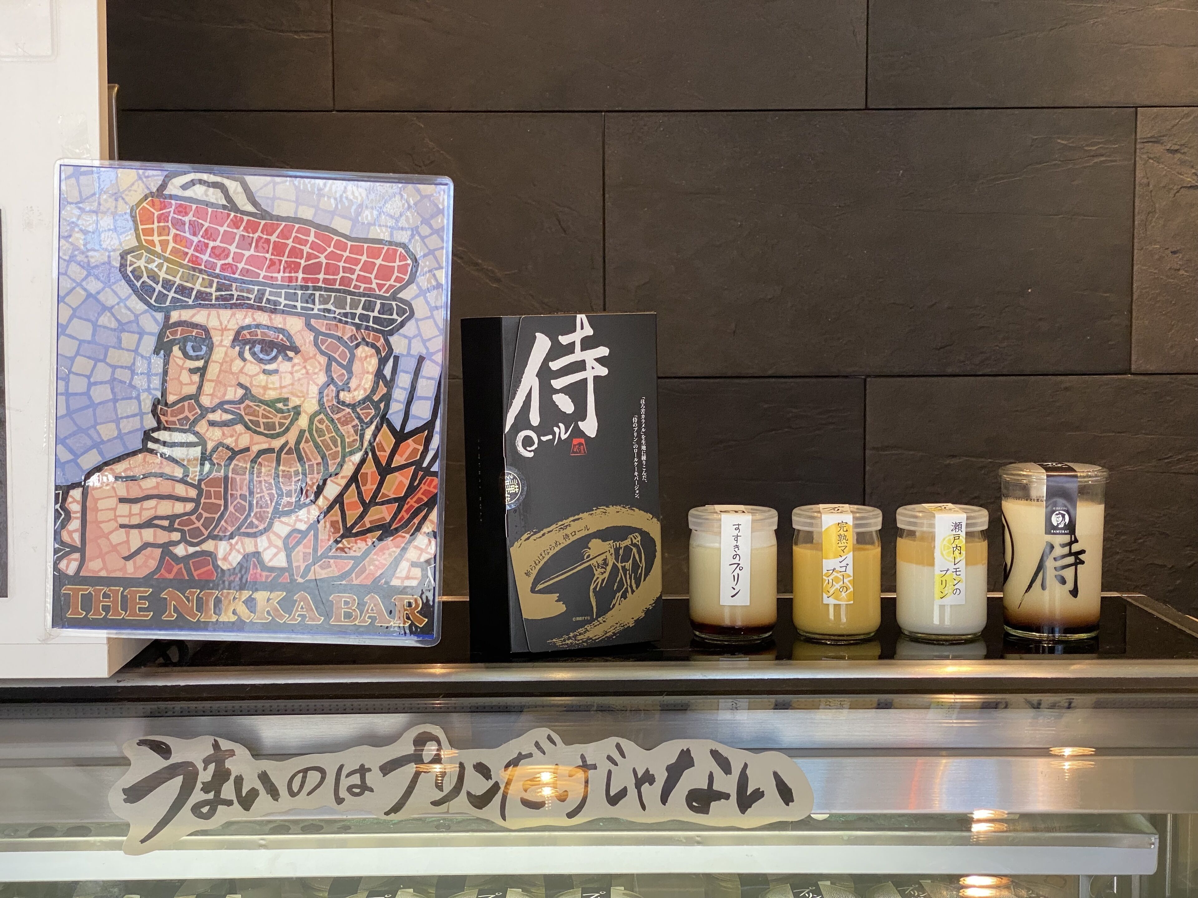 A bar counter with a mosaic artwork, a menu board, and several drink containers.