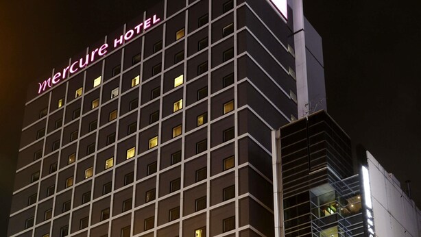 Een hoog hotel met een raster van ramen en een opvallend neonbord waarop 'Mercure Hotel' staat.