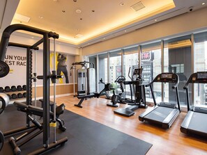 A gym with cardio machines, weightlifting equipment, and a large window with a city view. - Mercure Sapporo (Sapporo)