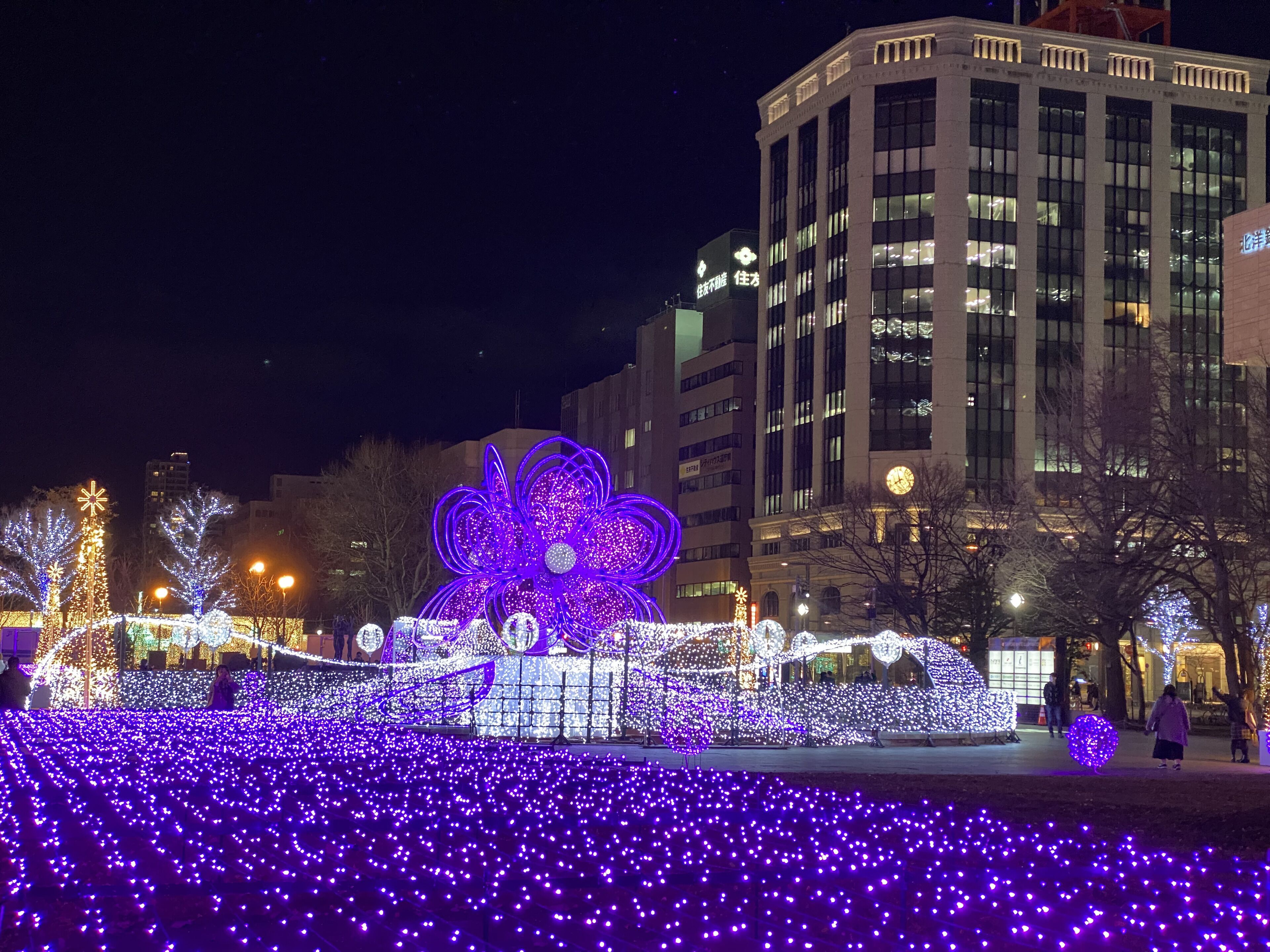 A large illuminated flower installation in an urban setting at night.