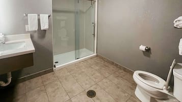 Un baño con cabina de ducha de vidrio, inodoro y lavamanos.