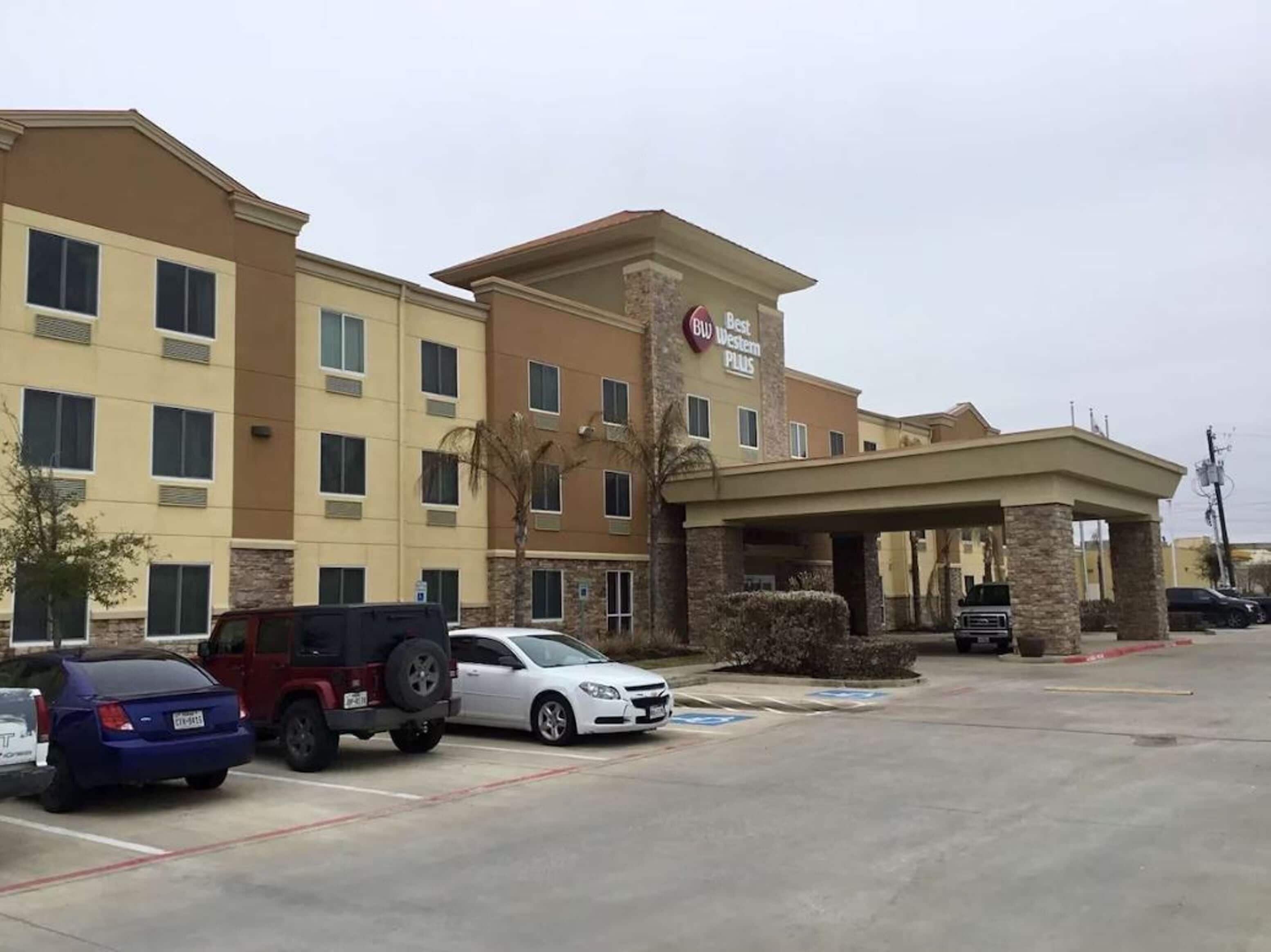 A hotel with a covered entrance, multiple parking spaces, and a sign indicating it is a Best Western Plus.