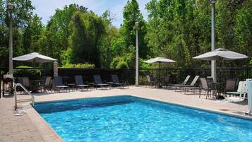 Una piscina al aire libre, sombrillas, sillones reclinables de piscina