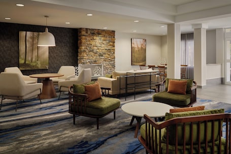 A modern hotel lobby with a stone accent wall, comfortable seating, and artwork on the walls.. Fairfield Inn & Suites by Marriott St. Augustine I-95
