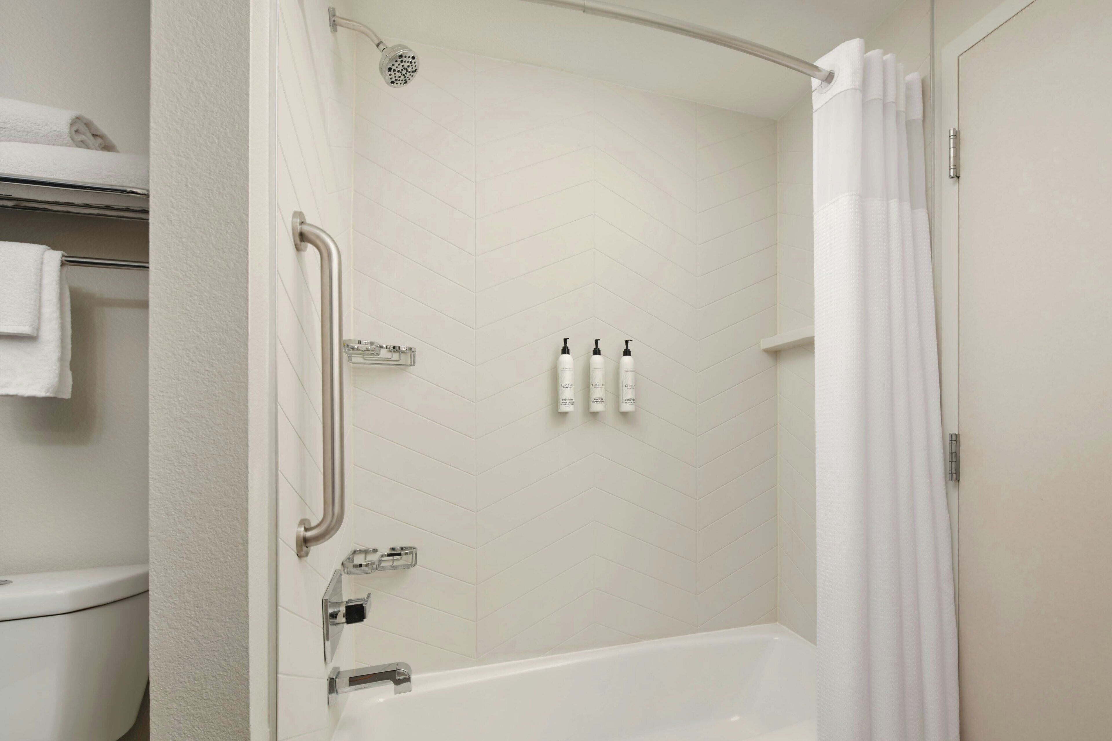A bathroom with a shower, toilet, and a towel rack.