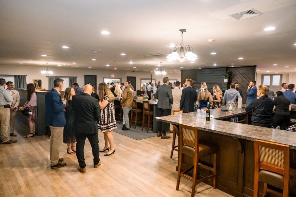 A spacious indoor area with a bar, wooden flooring, and modern lighting fixtures.