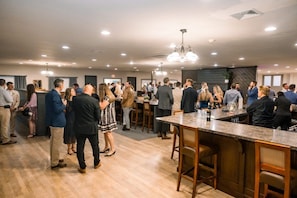 A spacious indoor area with a bar, wooden flooring, and modern lighting fixtures. - Harvest Drive Family Inn (Gordonville)