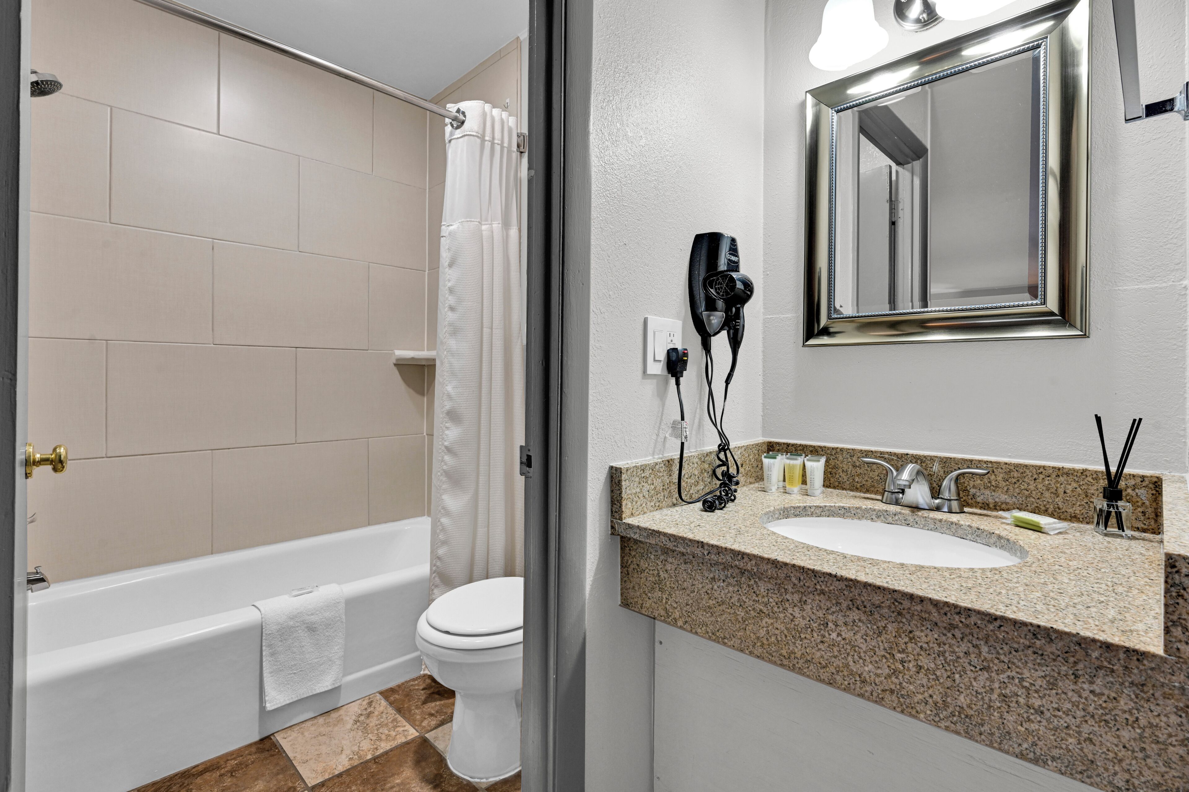 A bathroom with a bathtub, toilet, sink, and a hairdryer mounted on the wall.